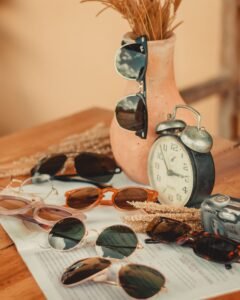 A collection of trendy sunglasses arranged with a vintage alarm clock for a stylish look.